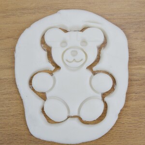 May include: White play dough with a teddy bear shape cut out of it.