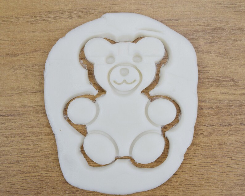 May include: White play dough with a teddy bear shape cut out of it.