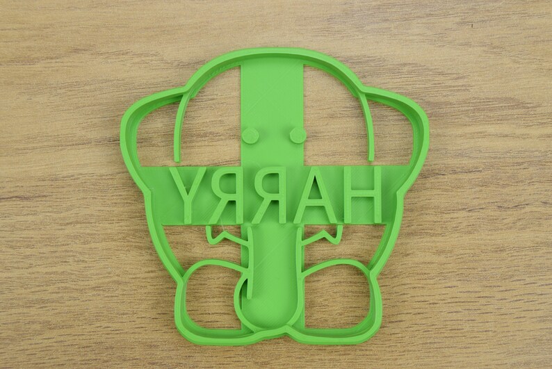 May include: Green plastic cookie cutter shaped like a cartoon character with the word "HARRY" written across the front.