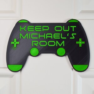 以下が含まれることがあります： 「Keep Out Michael's Room」という文字が書かれた、黒と緑のビデオゲームコントローラーの形をしたドアサイン。