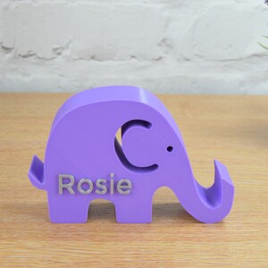 May include: A purple elephant figurine with a cutout of a crescent moon and the name "Rosie" engraved on the side.