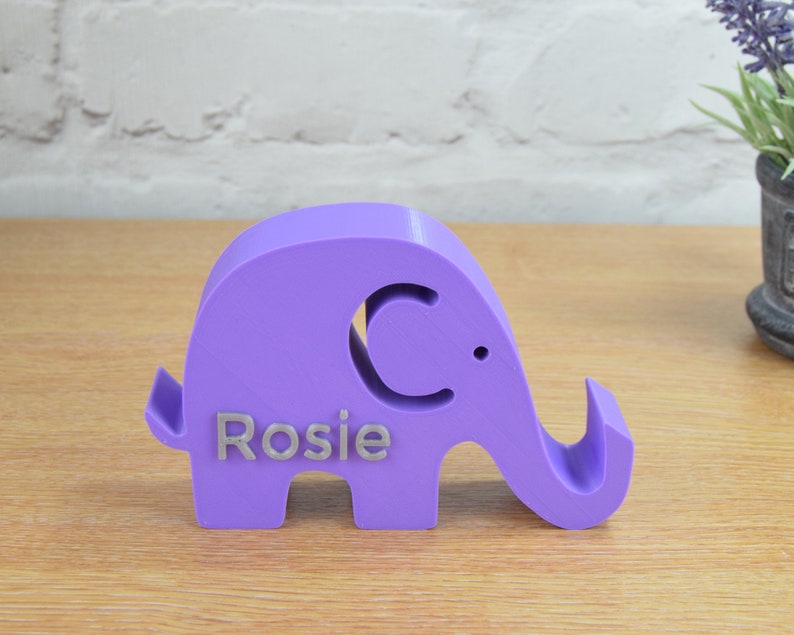 May include: A purple elephant figurine with a cutout of a crescent moon and the name "Rosie" engraved on the side.