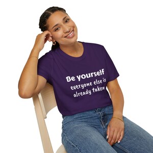 K&ouml;nnte beinhalten: Ein lila T-Shirt mit dem Text "Be Yourself everyone else is already taken" in wei&szlig;en Buchstaben.