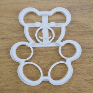 May include: White plastic cookie cutter shaped like a teddy bear with a simple face.