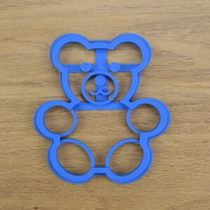 May include: Blue plastic cookie cutter shaped like a bear with a simple face.
