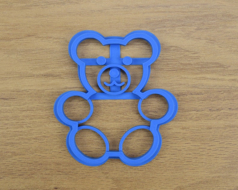 May include: Blue plastic cookie cutter shaped like a bear with a simple face.