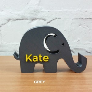 Pode incluir: Uma figura de elefante cinza com uma etiqueta de nome amarela que diz "Kate".