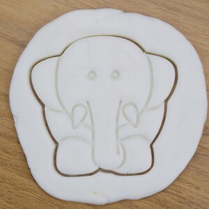 May include: White plastic cookie cutter shaped like an elephant with a simple design.