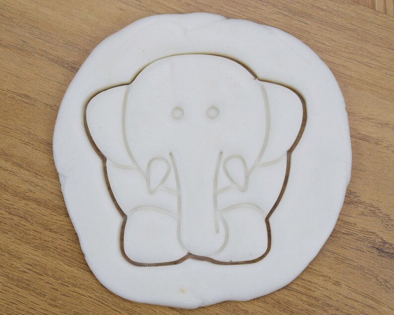 May include: White plastic cookie cutter shaped like an elephant with a simple design.