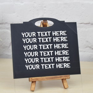 May include: A black chalkboard easel with the text "YOUR TEXT HERE" repeated six times in white lettering.