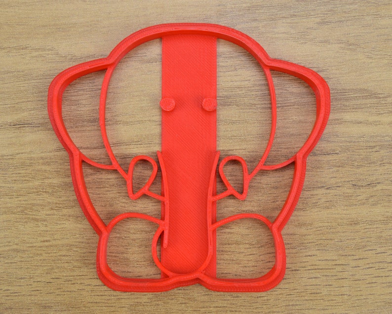 May include: Red plastic cookie cutter shaped like an elephant with a trunk and ears.