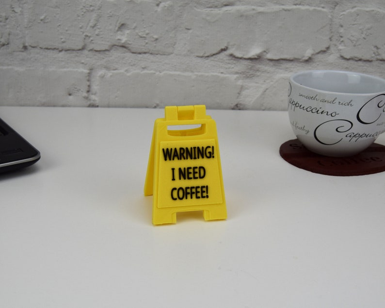 May include: Yellow warning sign with black text that reads "WARNING! I NEED COFFEE!"