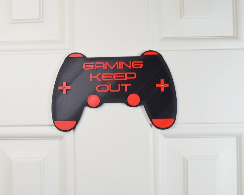 以下が含まれることがあります： 「Gaming Keep Out」というテキストが書かれた黒と赤のゲームコントローラーのサイン。