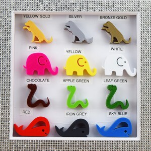 May include: A display of 12 colorful 3D printed animal figurines, each representing a different color. The animals include a dog, elephant, and snake. The colors are yellow gold, silver, bronze gold, pink, white, yellow, chocolate, apple green, leaf green, red, iron grey, and sky blue.