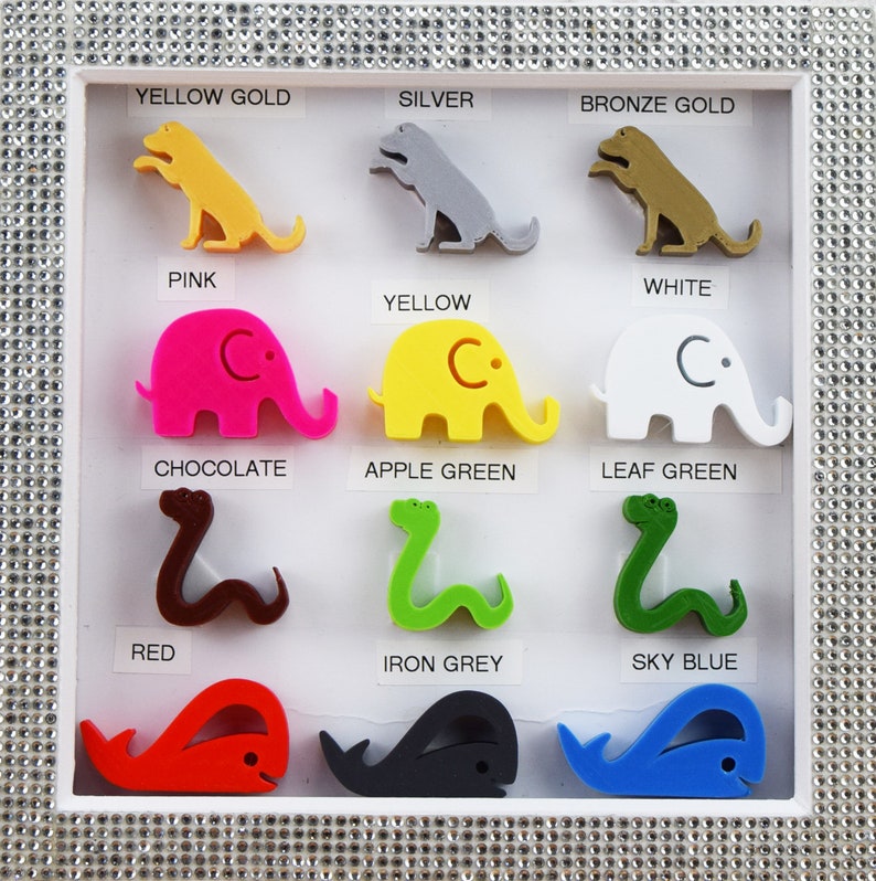 May include: A display of 12 colorful 3D printed animal figurines, each representing a different color. The animals include a dog, elephant, and snake. The colors are yellow gold, silver, bronze gold, pink, white, yellow, chocolate, apple green, leaf green, red, iron grey, and sky blue.