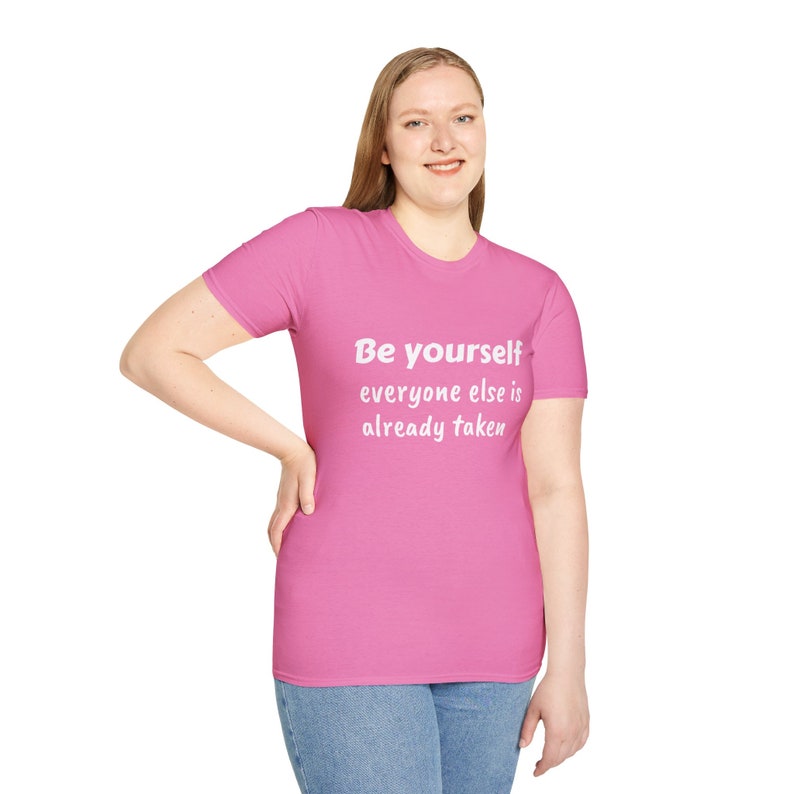 K&ouml;nnte beinhalten: Ein pinkfarbenes T-Shirt mit dem Text "Be yourself everyone else is already taken" in Wei&szlig;.