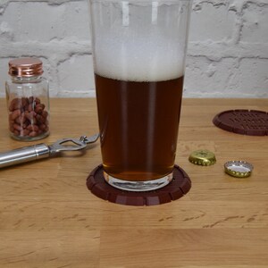 May include: A glass of beer on a brown coaster with the words "Your Words Here" on it. There are two bottle caps and a bottle of peanuts on a wooden table.