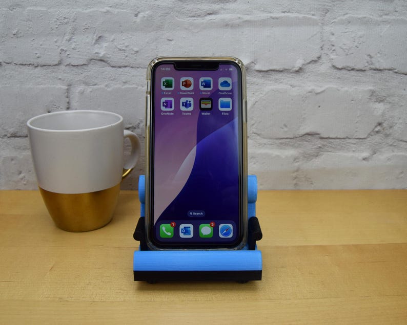 May include: A blue phone stand shaped like a chair, holding a smartphone with a blue and purple background and several app icons. The phone stand is on a wooden surface.