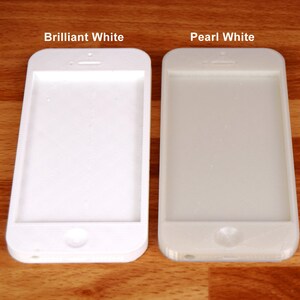 May include: Two white iPhone cases side-by-side. The case on the left is labeled "Brilliant White" and the case on the right is labeled "Pearl White".