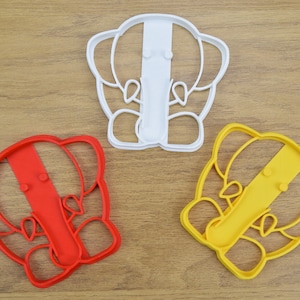 May include: Three cookie cutters shaped like elephants. The cutters are red, yellow, and white.