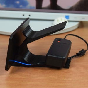 Pu&ograve; includere: Un supporto nero stampato in 3D con una striscia di luce LED blu. Il supporto &egrave; collegato a un adattatore di alimentazione nero con un indicatore LED rosso.