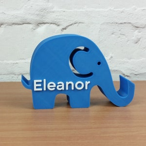 Pode incluir: Uma figura de elefante de pl&aacute;stico azul com o nome "Eleanor" impresso em branco no lado.