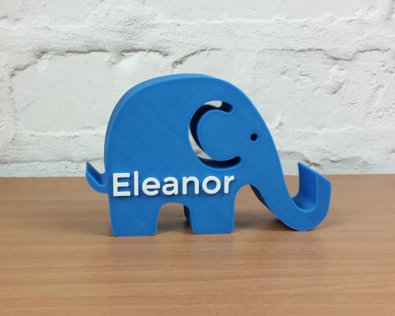 Pode incluir: Uma figura de elefante de pl&aacute;stico azul com o nome "Eleanor" impresso em branco no lado.