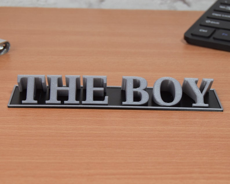 May include: A black plaque with the words "THE BOY" in raised silver letters.