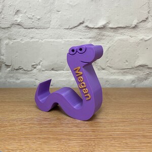 May include: Purple 3D printed worm with googly eyes and the name Megan written on the side.
