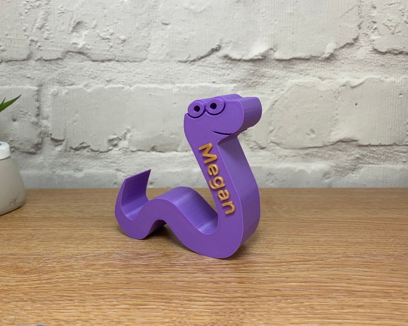May include: Purple 3D printed worm with googly eyes and the name Megan written on the side.