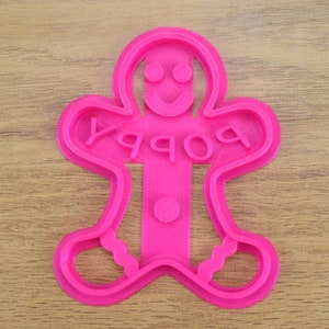 Puede incluir: Cortador de galletas de jengibre de pl&aacute;stico rosa con la palabra "Happy" escrita en &eacute;l.