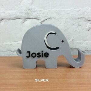 May include: A silver elephant-shaped phone stand with the name "Josie" printed on it.
