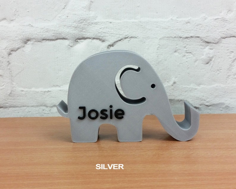 May include: A silver elephant-shaped phone stand with the name "Josie" printed on it.