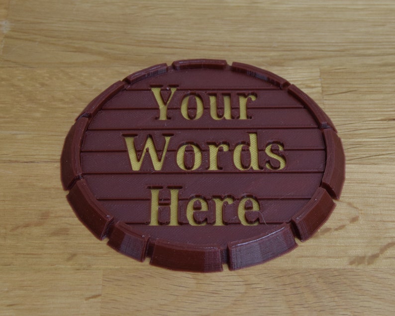 May include: A round, brown, 3D printed coaster with a raised edge. The coaster has the words "Your Words Here" engraved in yellow.