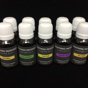 May include: Ten small amber glass bottles with white caps, each containing a different carrier oil. The bottles are labelled with the oil type, "SOOTHING INCENSES CARRIER OILS", and "THERAPEUTIC GRADE 15 ml (0.5 fl. oz)". The oils are: Jojoba, Cucumber, Castor, Grape Seed, and Sesame.