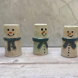 May include: A white ceramic mug with a black handle and the text "But First, Coffee" in a black, bold font. The mug is on a white surface.