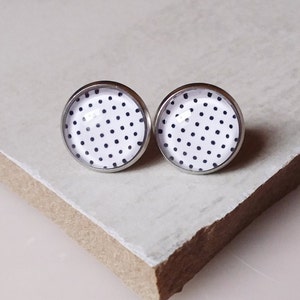 Könnte beinhalten: Ein Paar silberne Ohrstecker mit weißen und schwarzen Punkten.