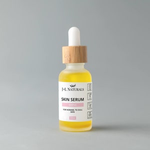 May include: A clear glass bottle with a bamboo lid and a yellow liquid inside. The bottle is labelled "J'L Naturals Skin Serum Shine For Normal to Dull Skin 1.0 fl oz".