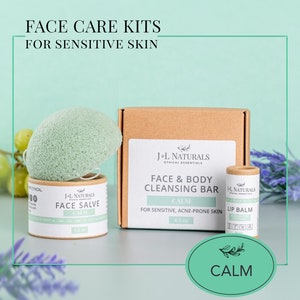 May include: A face care kit for sensitive skin with a green konjac sponge, a brown cardboard box labeled "J-L Naturals Face & Body Cleansing Bar Calm for Sensitive, Acne-prone Skin 4.5 oz", a brown cardboard tube labeled "J-L Naturals Lip Balm Calm", and a brown cardboard tube labeled "J-L Naturals Face Salve Calm 1.5 oz".