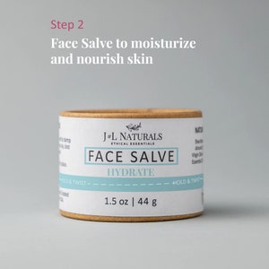 K&ouml;nnte beinhalten: Eine braune Pappr&ouml;hre mit einem wei&szlig;en Etikett, auf dem "J&L Naturals Ethical Essentials Face Salve Hydrate 1.5 oz | 44 g" steht.