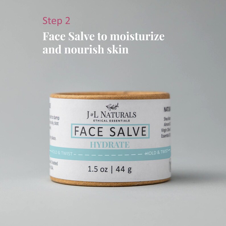 K&ouml;nnte beinhalten: Eine braune Pappr&ouml;hre mit einem wei&szlig;en Etikett, auf dem "J&L Naturals Ethical Essentials Face Salve Hydrate 1.5 oz | 44 g" steht.