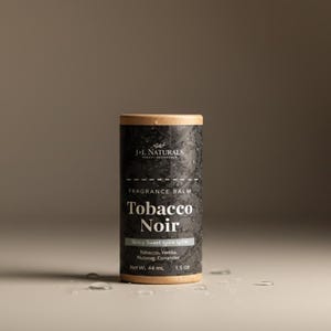 Puede incluir: Un envase cilíndrico de bálsamo perfumado con una etiqueta oscura y texturizada. La etiqueta presenta el texto "Tobacco Noir" y "Spicy Sweet Spice Spice". El envase es de 44 ml y 1,5 oz. La parte superior e inferior son de color marrón natural.