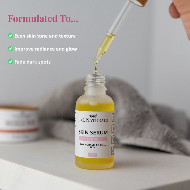 May include: A clear glass bottle of J-L Naturals Skin Serum with a dropper. The bottle is filled with a yellow liquid and has a white label with black text that reads "J-L Naturals Skin Serum Shine For Normal to Dull Skin 1.0 fl oz".