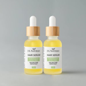 May include: Two amber glass bottles with bamboo caps and white labels. The labels read "J+L Naturals Hair Serum Lemongrass & Tea Tree For Healthier Hair & Scalp 1.0 oz".