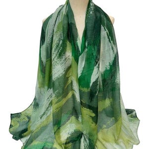 May include: A green and white abstract print scarf. The scarf is made of a lightweight fabric and has a flowing design.