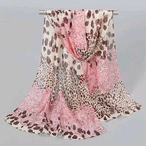 May include: A white, pink and brown patterned scarf with a leopard print design. The scarf is made of a lightweight, sheer fabric.