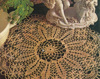 Op de afbeelding: Een grote, ronde, gehaakte doily in een lichtbruine kleur. De doily heeft een delicaat, ingewikkeld ontwerp met een centraal motief en stralende patronen.
