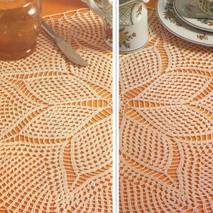 Könnte beinhalten: Eine gehäkelte Tischdecke mit einem zarten Blumenmuster in Creme. Die Tischdecke liegt auf einem Tisch mit einem Honigglas und einem Messer.