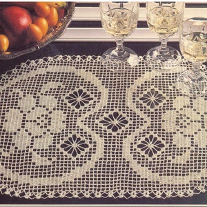 May include: An oval-shaped off-white crochet doily featuring a repeating geometric pattern with central flower-like motifs and a delicate scalloped edge. The intricate needlework creates an openwork grid design throughout the entire piece.