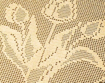 May include: A cream-colored crochet fabric featuring a repeating floral pattern created through a grid-like openwork stitch. The textile displays a consistent weave with dense areas forming the flower shapes and lighter areas forming the background.